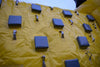 Image of Close-up of yellow inflatable obstacle course climbing wall with gray padded steps and sturdy hand grips for traction