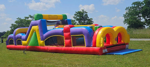 Colorful inflatable obstacle course rental set up outdoors on grass, perfect for races and backyard events
