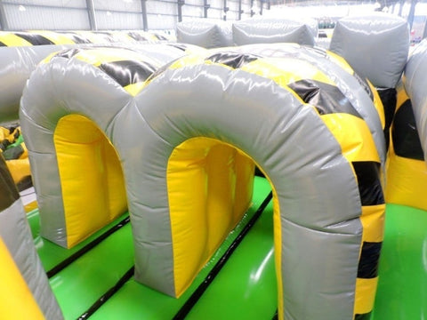 Overhead angled view of inflatable obstacle course tunnels with gray arches and yellow caution-striped design